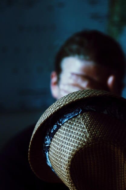 A dimly lit scene from a Swedish crime drama, showcasing a detective in a close-up shot, his face partially hidden in shadow. The background features a stark, minimalist Nordic interior, emphasizing the cold, isolated atmosphere.