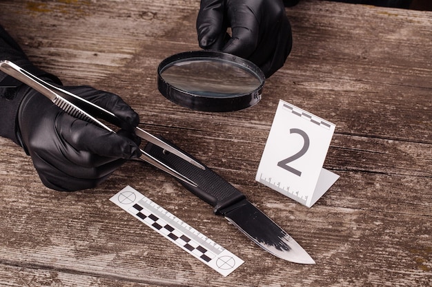 A detective piecing together a crime scene, photos and evidence spread across a table. The scene illustrates the meticulous investigation into the motivations behind the crime in an international drama.