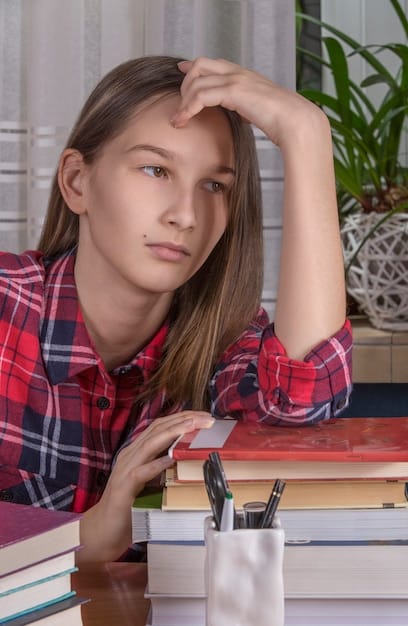 A close-up shot of a teenage girl's face, displaying a mix of determination and vulnerability. She is sitting at a desk, surrounded by books, with soft, natural lighting highlighting her features.